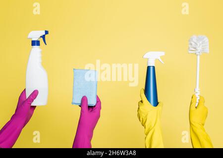 vue rognée des nettoyants contenant des flacons de pulvérisation avec détergent, chiffon et brosse de toilette isolés sur du jaune Banque D'Images