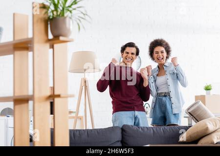 un couple interracial excités célébrant la réinstallation Banque D'Images