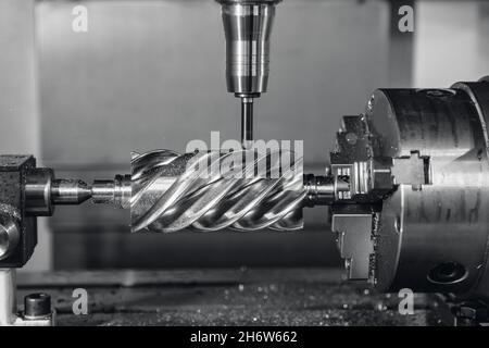 Usine industrielle la fraiseuse CNC traite les pièces à vis sans fin en acier avec des copeaux métalliques. Banque D'Images