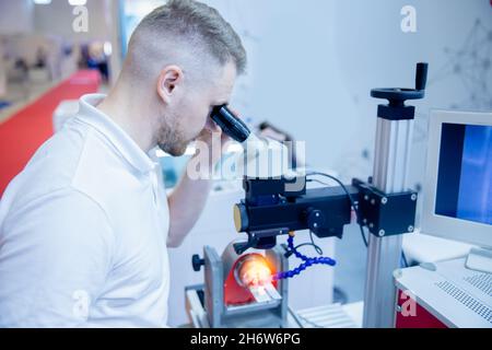 Les travailleurs industriels utilisent un microscope pour le soudage au plasma de précision au sol d'une usine moderne.Atelier de conception industrielle de métal. Banque D'Images