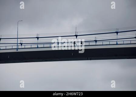 Deux personnes traversant un pont suspendu en Norvège, vu depuis un paquebot de croisière passant sous le pont Banque D'Images