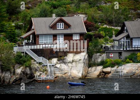 Maisons au bord de l'eau construites bien au-dessus du niveau de l'eau à côté d'un fjord norvégien Banque D'Images