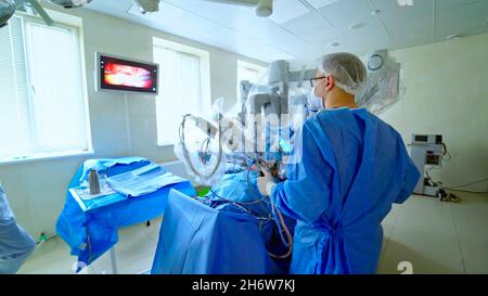 gros plan d'un médecin ou d'un chirurgien effectuant une opération sur un patient avec un robot chirurgical moderne tout en observant un moniteur. Banque D'Images