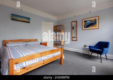 Cambridge, Angleterre - août 21 2019: Chambre à coucher dans la maison de l'époque victorienne britannique peu meublée avec juste lit, étagère et une chaise. Banque D'Images