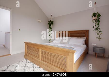 Dry Drayton, Angleterre - 2 août 2019 : chambre.Grand lit en bois et petite table décorée simplement dans des tons de blanc Banque D'Images