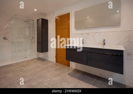 Clafring, Angleterre - avril 6 2020 : salle de douche bien éclairée dans une nouvelle maison récemment achevée avant la vente avec cabine de douche et lavabos muraux Banque D'Images