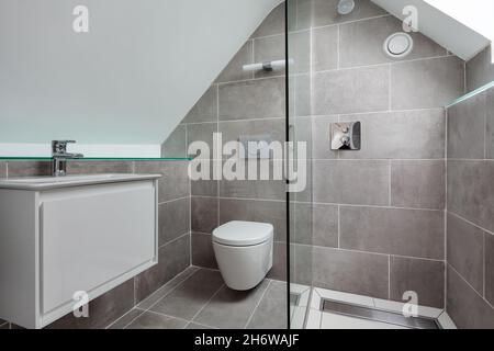 Cambridge, Angleterre - juillet 31 2019: Salle de douche avec sol carrelé et murs avec toit en pente, toilettes et lavabo Banque D'Images