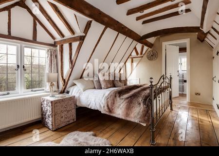 Essex, Angleterre - janvier 18 2019: Chambre à coucher fortement poutres apparentes avec plafonds en pente et plancher d'origine avec lit en fer Banque D'Images