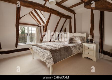 Essex, Angleterre - janvier 18 2019 : chambre avec poutres apparentes, alcôve de veuve et lit en bois habillé avec table latérale Banque D'Images