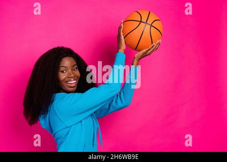 Photo de funky jolie peau sombre femme habillé bleu sweat-shirt sourire jouant basket-ball isolé couleur rose fond Banque D'Images