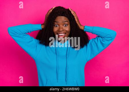 Photo de doux impressionné peau sombre dame porter bleu sweat à capuche bras tête sourire isolé couleur rose fond Banque D'Images