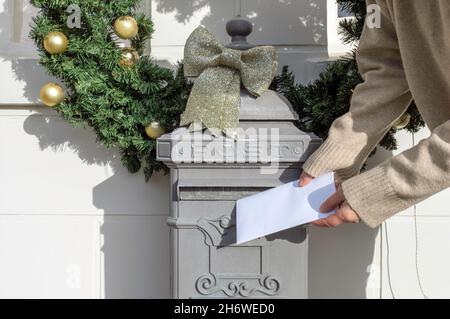 Main tient une lettre et met dans une boîte aux lettres à l'ancienne près de la maison le jour de l'an Banque D'Images