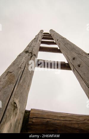 Ancienne échelle en bois sur la prairie menant en haut dans le ciel.Échelle au ciel.Symbole de carrière. Banque D'Images