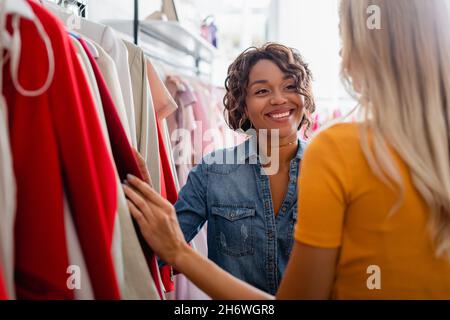 un bon assistant de boutique afro-américain qui regarde un client blond dans une boutique Banque D'Images