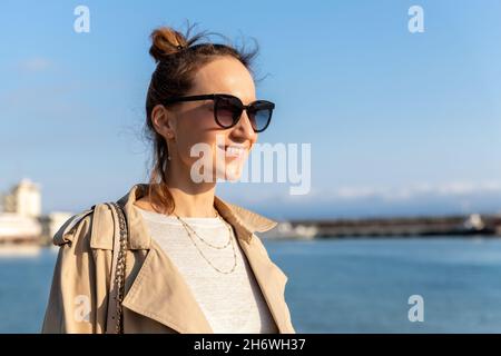 Jeune adulte tendance élégant belle caucasienne heureuse femme souriante appréciez la marche à côté de Yalta mer remblai le chaud jour ensoleillé.Portrait de femme Banque D'Images