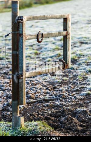 Fers à cheval suspendus sur une porte ouverte de pâturage lors d'un matin ensoleillé d'hiver.Symbole de bonne chance, charme chanceux dans les sports équestres et l'élevage de chevaux. Banque D'Images