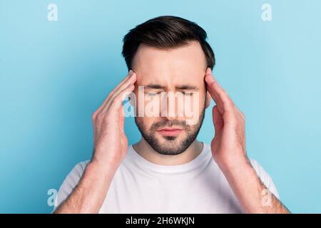 Gros plan portrait d'attrayant déprimé désespéré gars se sentant mal de tête terrible isolé sur fond bleu vif couleur pastel Banque D'Images