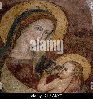 Saint Mary suce le bébé Jésus dans ce détail carré d'une fresque lombardique de la Vierge médiévale tardive et de l'enfant dans l'ancienne Chiesa dei Santi Giovanni e Reparata (église des Saints John et Reparata) à Piazza San Giovanni, Lucques, Toscane, Italie.La basilique, aujourd’hui musée, a été reconstruite au XIIe siècle sur le site d’anciens bâtiments romains et d’une ancienne église chrétienne et baptistère qui a servi de cathédrale originale de la ville. Banque D'Images