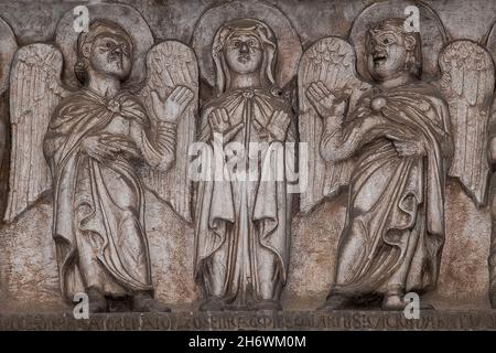 La Vierge Marie, flanquée d'anges sculptés, prie au-dessus d'une inscription latine sur l'architravée ou le faisceau de l'AD 1187 porte centrale romane de l'ancienne Chiesa dei Santi Giovanni e Reparata (église des Saints John et Reparata) sur la Piazza San Giovanni à Lucca, Toscane, Italie.La porte richement sculptée a survécu à la reconstruction de la façade en 1589. Banque D'Images