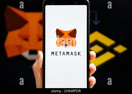 Ukraine, Odessa - octobre, 9 2021: Main tenant mobile avec l'application MetaMask en cours d'exécution à l'écran de smartphone avec MetaMask et le logo Binance en arrière-plan.Co Banque D'Images