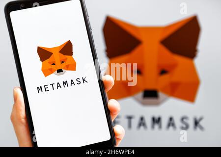 Ukraine, Odessa - octobre, 9 2021: Main tenant mobile avec l'application MetaMask fonctionnant à l'écran de smartphone avec le logo MetaMask en arrière-plan.MetaMask l'est Banque D'Images