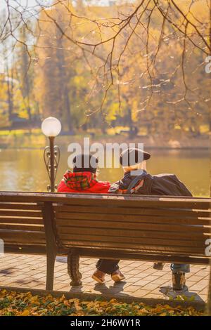 Vue arrière d'un couple senior aimant sur le banc du parc en automne par beau temps Banque D'Images