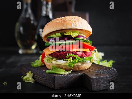 Hamburgers de betteraves végétaliennes sains avec tomate, concombre, oignon rouge et sauce.Arrière-plan sombre.Copier l'espace. Banque D'Images