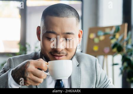 homme d'affaires asiatique souriant avec café tatouage au bureau Banque D'Images