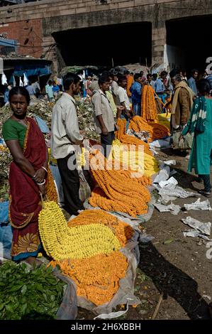 Commerçants sur le marché aux fleurs de Howrah avec des marigolds et des puja offrandes, Kolkata, Inde Banque D'Images