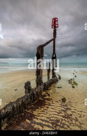 vieux brise-lames en bois ou groyne sur une plage côtière de l'île de wight avec ciel atmosphérique orageux, paysage marin sur le rivage de l'île de wight. Banque D'Images