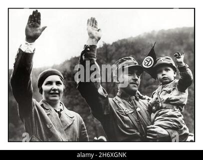 Archive sa Sturmabteilung années 1930 la famille allemande nazie de trois saluant le Heil Hitler, avec le père portant l'uniforme de la sa Sturmabteilung chemises brunes paramilitaires aile nazie.Son fils portant un uniforme de nourrisson similaire agitant le fant du drapeau de l'Allemagne nazie sa Sturmabteilung.La famille allemande Aryan des années 1930 considérée comme idéale Banque D'Images