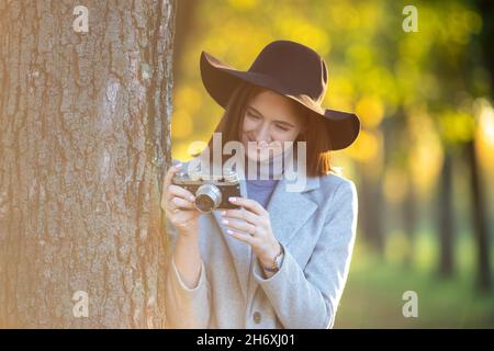 Portrait d'une fille à tête rouge prenant des photos avec l'ancienne caméra analogique dans le parc en automne Banque D'Images