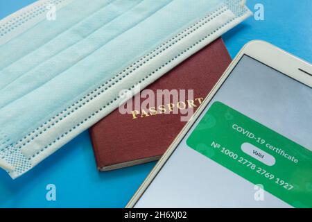 Gros plan sur l'écran d'un smartphone avec un certificat de vaccination numérique Covid-19 valide.À côté du passeport et du masque médical Banque D'Images