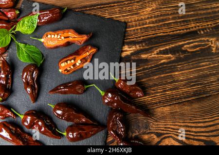 Piment sur fond de bois.piment très chaud.Chocolat Naga Bhut Jolokia.Épices exotiques.Ingrédients chauds pour la nourriture. Banque D'Images