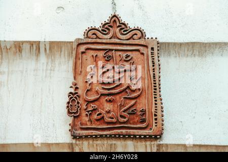 Panneau métallique avec hiéroglyphes arabes sur un mur texturé avec des taches Banque D'Images