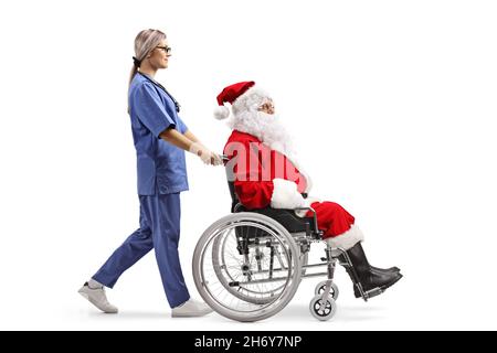 Vue en profil d'une infirmière qui marche et pousse le père noël dans un fauteuil roulant isolé sur fond blanc Banque D'Images