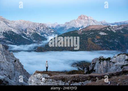 Un touriste se dresse au-dessus du brouillard au bord d'une falaise dans les Dolomites.Emplacement Auronzo rifugio dans le parc national de Tre Cime di Lavaredo, Dolomites, Trentin-Haut-Adige, Italie Banque D'Images