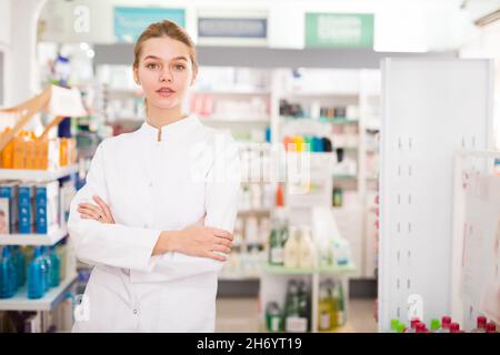 Une femme gaie pharmacien debout avec les bras croisés à l'intérieur de la pharmacie Banque D'Images