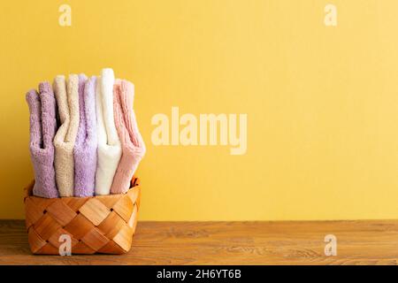 Serviettes de bain dans un panier sur une table en bois. Fond jaune. Espace de copie Banque D'Images