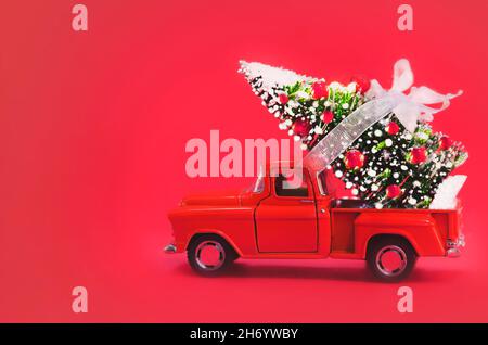 Voiture rouge portant l'arbre de Noël sur un fond rouge.Arrière-plan de Noël.Photo de haute qualité Banque D'Images