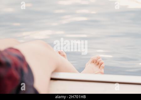 femme assise sur un quai, éclaboussant ses orteils dans le lac pour se rafraîchir et se détendre Banque D'Images