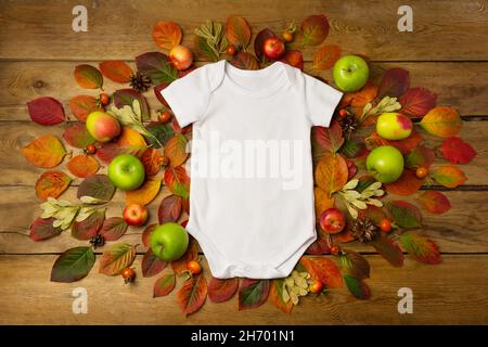 Coton blanc bébé manches courtes onesie rustique maquette avec feuilles d'automne, pommes et cônes de pin.Modèle de combinaison neutre et design, barboteuse pour nouveau-né Banque D'Images