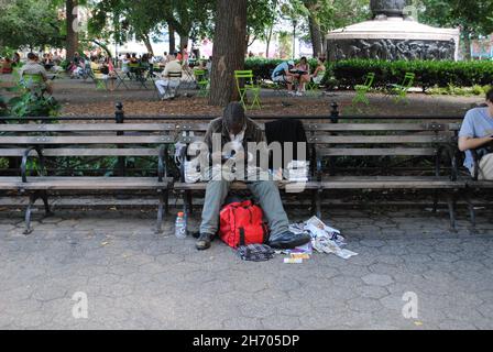 Un homme sans abri est assis sur un banc de la place Union avec tous ses effets personnels. Banque D'Images