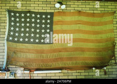 Le vieux drapeau américain en lambeaux est suspendu sur une petite Grange Banque D'Images