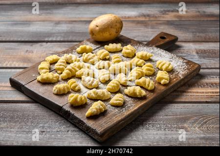 Gnocchi de pomme de terre cru non cuit avec farine sur planche à découper en bois sur table rustique, mise au point sélective.Cuisine maison Banque D'Images