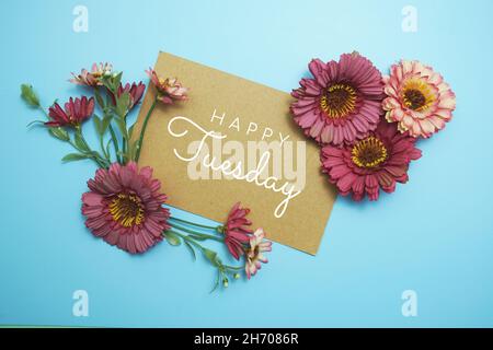 Texte typographique de la carte Happy Tuesday avec bouquet de fleurs sur fond bleu Banque D'Images