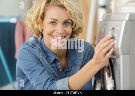 une jeune femme utilise un lave-linge Banque D'Images