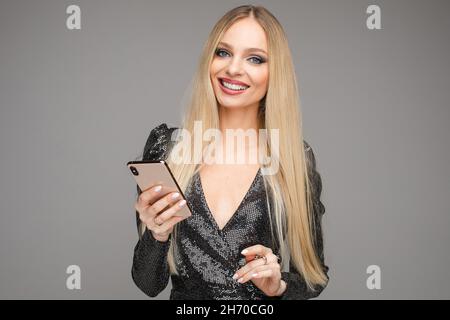 Une jolie femme souriante tenant un téléphone portable dans un studio Banque D'Images