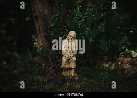 Statue de jeune fille avec col cassé dans un cadre de forêt de moody Banque D'Images