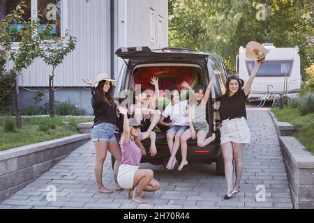 Femmes debout près de la voiture, enfants assis dans le coffre de voiture Banque D'Images